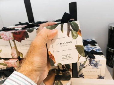 Roppenheim, Fransa - 11 Temmuz 2023: Bir adam parfümlerle dolu bir mağazadan lüks kokulu bir mum seçer. Jo Malone markası bu cazip seçimde zarafet ve kalite sunuyor Myrrrh.
