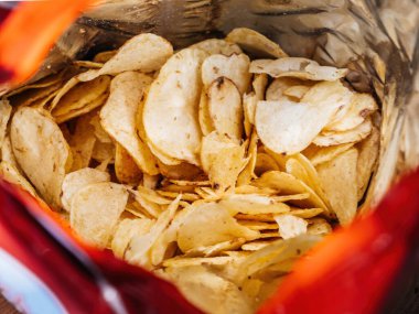 Abur cubur kadar mükemmel bir tabakta paketlenmiş tuzlu kırmızı biber patates cipsi yakın plan..