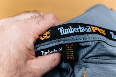 Hamburg, GErmany - 16 Şubat 2022: Dayanıklılıkları ve güvenilirlikleriyle bilinen Timberland Pro iş donlarının içindeki etiketi inceleyen bir erkek el