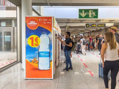Seyahat eden insanlar, İspanya 'daki PMI Palma de Mallorca Havalimanı' ndaki özel makinelerden su satın alıyorlar.