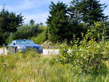 Mummelsee, Almanya - 17 Eylül 2023: Lüks, üstü açık bir Bentley araba tenha, vahşi bir yere park edilmiş, doğal çevrenin aksine araçların zarafetini ön plana çıkarıyor.