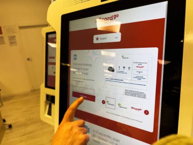 Mallorca, İspanya - 22 Haziran 2023: Bir erkek el, yaklaşan tatil kaçamağı için yeni bir SUV rezervasyonu yapmak üzere otomatla etkileşime geçiyor