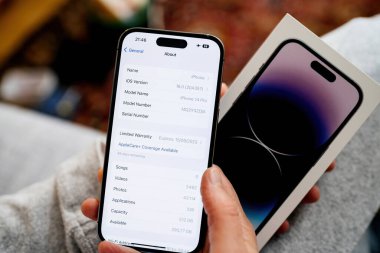 Londra, Birleşik Krallık - Bölüm 28, 2022: Bir kadın en son iPhone 14 Pro 'yu elinde tutarken görülüyor, depolama kapasitesi ve iOS sürümü hakkında titizlikle bilgi topluyor..