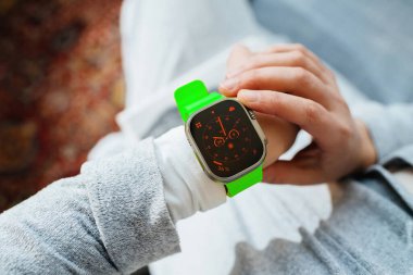 Londra, Birleşik Krallık - 20 Ekim 2023: Bir kadın Apple Watch Ultra 2 'nin bileklerine taktığı yeni dijital görüntüsünü incelikle inceliyor.
