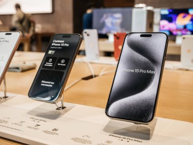 Paris, Fransa - 22 Eylül 2023: Apple Computers tarafından piyasaya sürülen bir dizi yeni çıkan titanyum iPhone 15 Pro akıllı telefon bir Apple Store 'da sergilenmekte olup, arka planda müşteriler aktif olarak alışveriş yapmaktadır.