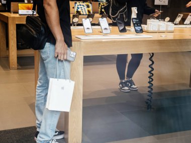 Paris, Fransa - 22 Eylül 2023: Bir müşteri içinde yeni iPhone 15 Pro bulunan bir kesekağıdını mağazada sergilenen son iPhone modellerinin tam menzilinin yanında tutuyor..
