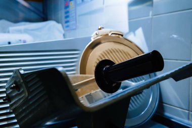 Profesyonel bir mutfak dilimleyicisi, temiz mavi bir arkaplanda titizlikle muhafaza edilen bir endüstriyel restoran mutfağında bulunur.