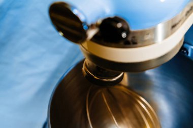 Mutfak gereksinimleri: Metal eklentileri olan el değmemiş bir karıştırma kabı mavi bir arka planda ayarlanır ve bir sonraki karıştırma işlemine davet edilir.