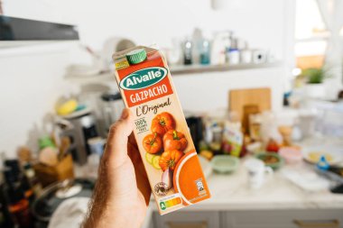 Frankfurt, Almanya - 12 Haziran 2023: Bir erkek eli, ferahlatıcı bir yaz günü ikramı için hazırlanan orijinal bir Alvale Gazpacho paketini mutfakta tutuyor.