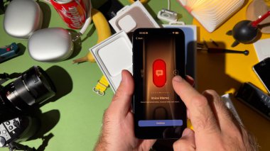Londra, İngiltere - 25 Eylül 2023: Yaratıcı olarak tasarlanmış bir odada yeni titanyum iPhone 15 Pro ses notu için Action düğmesiyle etkileşime giren bir erkek elinin yakın çekimi