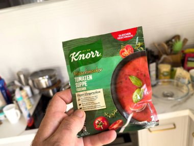 Londra, İngiltere - 28 Sep 2023: Bir erkek eli bir mutfak ortamında lezzetli bir domates çorbası olan Knorrs Tomaten Suppe paketini elinde tutuyor.