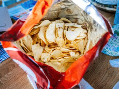 Cipslerle dolu açık bir paketin detaylı makro çekimi. Lezzetli ve tuzlu patates atıştırmalıkları sergileniyor..
