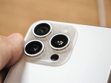 Paris, Fransa - Bölüm 22, 2023: Bir erkek, yeni 5x kamera yakınlaştırma özelliğine odaklanarak, Elma iPhone 15 Pro Max 'in beyaz titanyum gövdesini dikkatle inceliyor