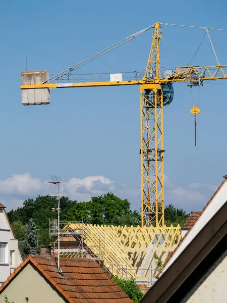 新しい家の仕上げのタッチは 屋上建設現場の高い黄色いクレーンの絶え間ない努力によって可能になります — ストック写真