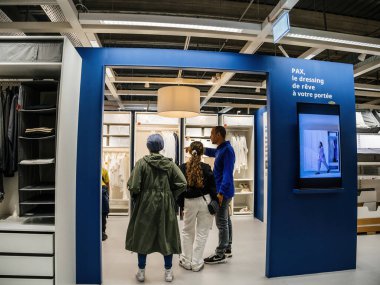 Paris, Fransa - 31 Ağustos 2023: İsveçli IKEA perakendecisinin içinde, bir anne ve kız, bir çalışan tarafından bir Pax giysi dolabı mobilya ünitesi satın almak için şahsen yönlendiriliyor..