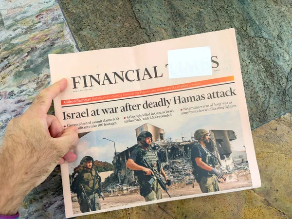 stock image Paris, France - Oct 9, 2023: POV male hand reading Financial Times edition headline Israel at waar after unprecendent assualt - Gaza - Israel conflict . Palestinian militant groups led by Hamas