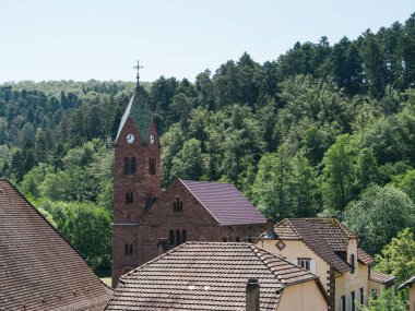 Açık bir yaz gününde gökyüzü perspektifi, Eglise Protestan Graufthal 'ı köknar ağaçlarının arka planına karşı çeker.