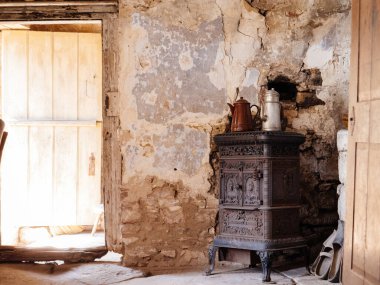 Demir alaşımlı metal soba ısıtıcısı, eskimiş bir duvara dayanıyor, yakındaki ahşap ayakkabılarla uyumlu, Aztek 'lerin yaşam tarzını anımsatıyor.