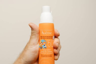 Paris, Fransa - 30 Mayıs 2023: Erkekler el yapımı turuncu bir güneş kremi şişesi sergiliyor.