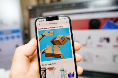 Paris, Fransa - 12 Temmuz 2023: Güçlü erkek eller Amazon İspanya 'nın web sitesindeki Prime Day' i sembolize ederek İspanyol metinleriyle süslenmiş birden fazla Amazon Prime paketini kavrıyor