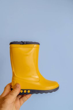 Paris, Fransa - 1. Sezon 2023: Bir erkek el Nora markalı sarı botları zıt beyaz ve mavi arka planda tutuyor.