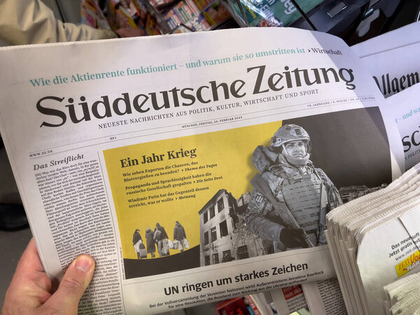 Frankfurt, Germany - Feb 24, 2023: A hand is holding a copy of the Suddeutsche Zeitung newspaper. The prominent headline translates to One Year of War. The page features an image of a soldier in