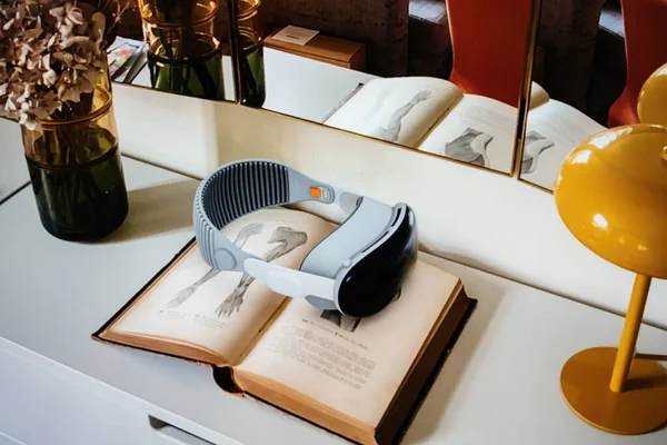 2023年6月6日 法国巴黎 苹果最新的Vision Pro耳机被放置在带有插图页的开放图书之上 布景在一张白色的桌子上 旁边放着一只花瓶 上面插着干枯的花 — 图库照片