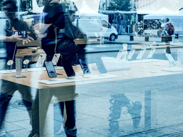 Paris, Fransa - 22 Eylül 2023: Apple Dâhisi 'nin iPhone 15' i satın alırken müşteriye yardımcı olması nedeniyle yayaların siluetleri Apple Store 'un camına yansıtılıyor