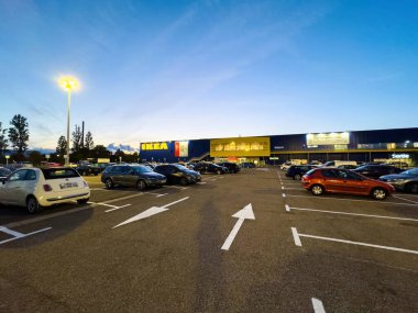 Strasbourg, Fransa - 3 Ekim 2023: Karanlık çöktüğünde geniş ölçekli bir çekim IKEas mobilya deposunu yakalıyor, arabalar düzgün park edilmiş ve asfaltın altına temiz yönlü oklar çizilmiş.