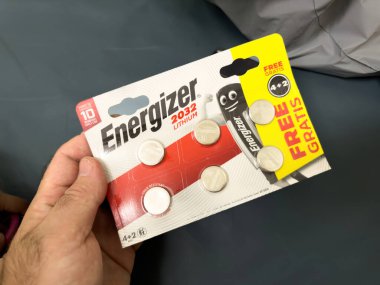 Paris, Fransa - 25 Ekim 2023: Erkeklerin bakış açısına göre, bir el 6 adet CR-2032 lityum pili içeren ve özellikle 2 adet ek aküden oluşan bir paket tutar.