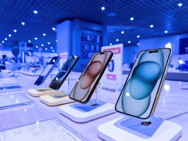 Strasbourg, France - Oct 1, 2023: A hero object view showcasing a row of the latest iPhone 15 Pro smartphones prominently, with the vast interior of the FNAC store forming the backdrop clipart
