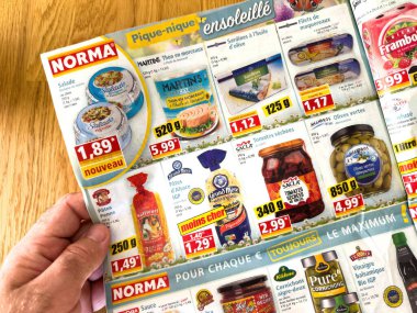 Paris, Fransa - Sep 28, 2023: Bir erkek el ele tutuşuyor ve Fransa Norma Supermarket 'ten gelen bir reklam kağıdını okuyor.