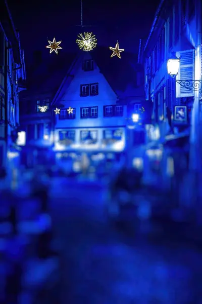 Strasbourgs streets under a blue color cast, blurred with Christmas lights, create a dreamy scene during the festive market season
