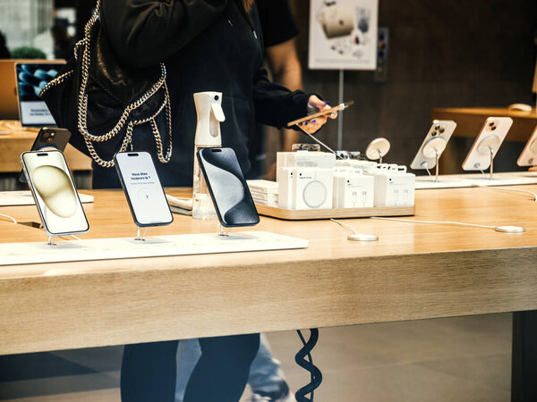 Париж, Франция - 22 сентября 2023: Низкоугольный вид снимает женщину, тестирующую новейший смартфон Apple iPhone 15 Pro, ориентированный на функции устройств в магазине