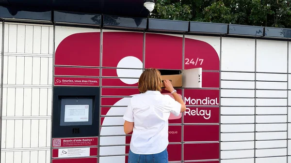 フランス 2023年9月22日 オンラインショッピング注文の利便性を象徴するモンディアルリレーロッカーから小包を取得する女性のリアビュー — ストック写真