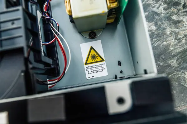 An image of a laser device with a warning sticker indicating the hazard, with wires and components visible inside - hi-fi high wnd cd-player