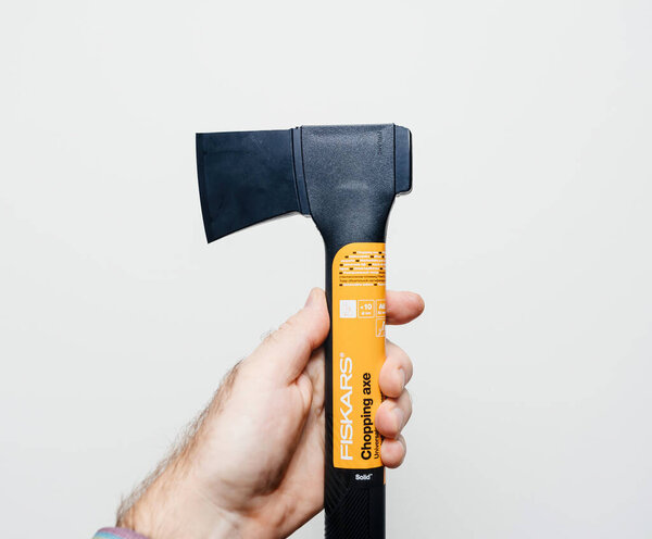 POV of a male hand holding a new Fiskars chipping axe against a white background, showcasing the design and build of the tool
