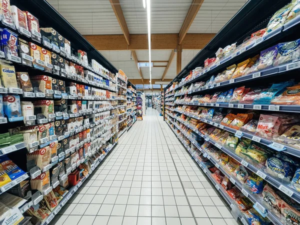 stock image Paris, France - Nov 10, 2023: A perspective view over an extended aisle in a supermarket featuring sweets, candies, and chocolate department with endless shelf choices