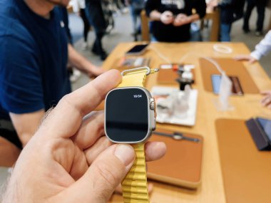 Paris, Fransa - 23 Şubat 2022: Bir Apple Store 'da, alkışlanan saat, arka planda ürün popülerliğini vurgulayan bir müşteri alışverişi ile zamanı 16: 54 olarak gösteriyor.