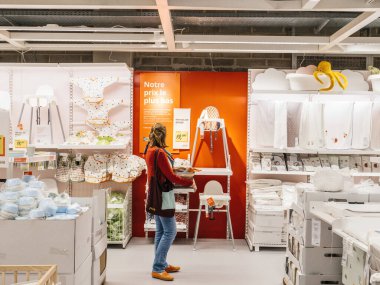 Paris, Fransa - 31 Ağustos 2023: Issız bir kadın, İsveç mobilya süpermarketinin ortasında bir anlık tefekkür sonucu bir IKEA mağazasında bebek sandalyesine bakıyor.