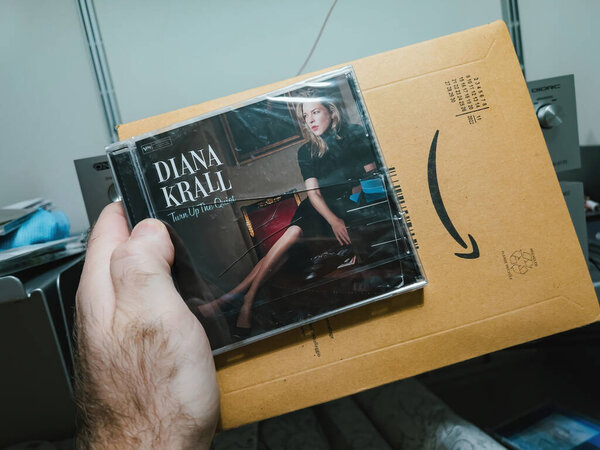 Париж, Франция - 21 декабря 2022: Мужская рука держит поврежденную Amazon Prime посылку, содержащую Turn Up the Quiet Дианы Кролл, со сломанным футляром для драгоценностей CD