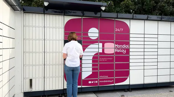 フランス 2023 女性はモンディアルリレーロッカーからパッケージを取るためにバーコードを挿入しています 配信サービスでの技術の統合を強調 — ストック写真