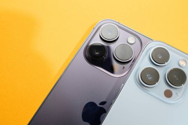 Paris, France - Sep 29, 2022: A close-up view of two luxury Apple iPhone models, 13 Pro and 14 Pro, placed side by side against a yellow background, highlighting their features