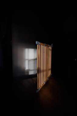 A morning scene featuring a safety baby gate open near a staircase, bathed in sunlight, with a whasto on the adjacent wall