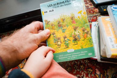 Paris, France - Dec 16, 2023: An overhead view of a father pointing to the DVD package of Family - A Tales from Japan to his toddler, sharing a moment