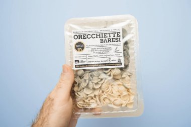 Paris, France - Dec 20, 2023: A male hand holds a package of Orecchiete Baresi pasta manufactured by Marziale, with the contents perished and covered in mold