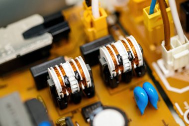 Elektronik bileşenlerin, kondansatörlerin, bobinlerin ve karmaşık devrelerin yakın çekim görüntüsü muhtemelen tüketici elektroniğinin bir parçası içinde..
