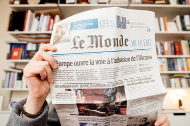 Frankfurt, Almanya - 20 Aralık 2023: Oturma odasında Le Monde gazetesi okuyan bir kadın, savaş bağlamında Avrupa 'nın Ukrayna' ya verdiği desteği kapsayan bir başlık attı.