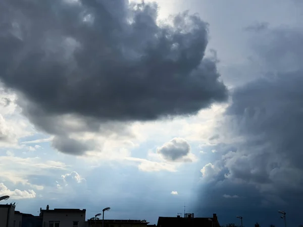 都市のスカイラインの上に暗い雲が浮かび上がり 光が通る光が通過し 近づく嵐を伝える — ストック写真