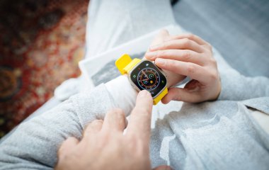 Londra, Birleşik Krallık - Sep 28, 2022: Bir üstten çekim, kadına yeni Apple Watch Ultra 2 kol saatini OLED ekranıyla gösteren bir erkek eli görüntüler. Keskin teknoloji sergileniyor